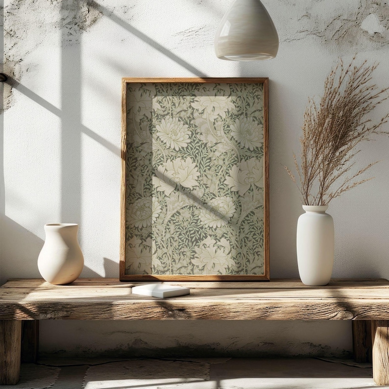 May include: A framed print of a vintage floral pattern in shades of green and white. The print is displayed on a wooden shelf with a white vase and dried grasses.