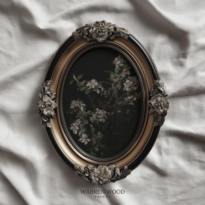 May include: An oval framed print featuring a floral botanical design. The frame is black and gold with ornate floral accents. The print has a dark background with white flowers and green leaves. The text "WARREN WOOD PRINTS" is at the bottom.