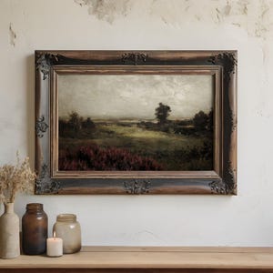 May include: An antique landscape painting in a dark wood ornate frame. The artwork depicts a field with trees and a cloudy sky. The painting has a vintage aesthetic and is displayed on a wooden surface.