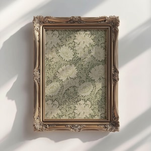 May include: A gold ornate frame with a floral print inside. The print features a repeating pattern of white flowers and green leaves.