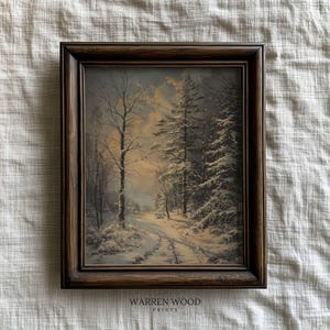 May include: A framed print depicting a winter scene with snow-laden trees and a path. The artwork is encased in a dark brown wooden frame. The text "WARREN WOOD PRINTS" is printed at the bottom of the frame.