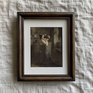 May include: Framed sepia-toned print featuring a young person drinking from a large mug in a kitchen setting. The print is set within a dark brown wooden frame with a white mat. The text "WARREN WOOD PRINTS" is printed at the bottom.