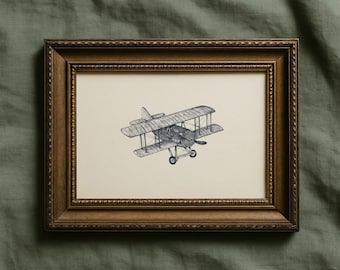 May include: A framed black and white illustration of a biplane. The artwork is in a rectangular, ornate, brown wooden frame. The biplane is drawn in detail, with visible wings, propeller, and wheels. The background is a neutral cream color.