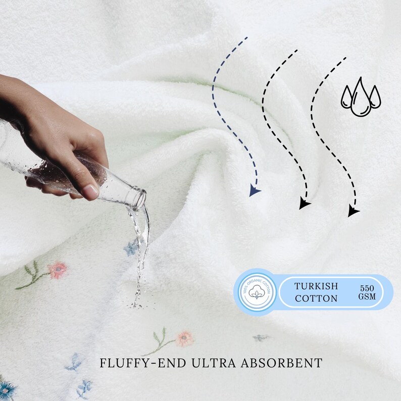 May include: White Turkish cotton towel with a floral embroidery design. The towel is ultra absorbent and has a 550 GSM weight. Water is being poured onto the towel to demonstrate its absorbency.