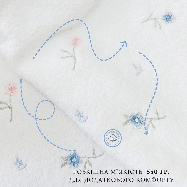 May include: White organic cotton towel with embroidered flowers in blue and pink. The towel is 550 grams and features a label that says "100% Organic Cotton".