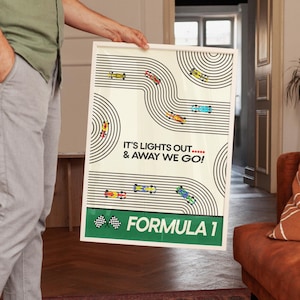 May include: A framed Formula 1 poster with a cream background and a black and white race track design. The poster features colorful race cars and the text "IT'S LIGHTS OUT... & AWAY WE GO!" and "FORMULA 1".
