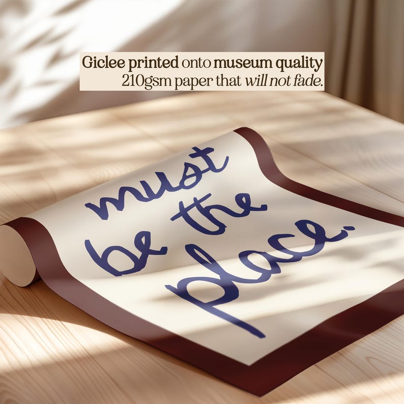 May include: A rolled print featuring the phrase "must be the place" in blue script. The print has a cream-colored background and a dark brown border. Text at the top states "Giclee printed onto museum quality 210gsm paper that will not fade."