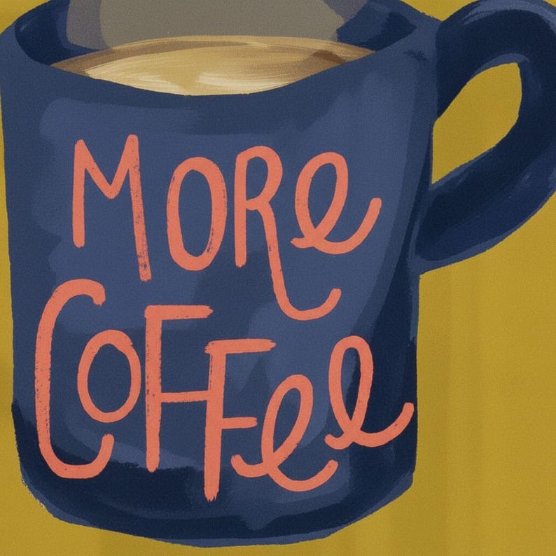 a blue mug with the text "More Coffee" written on it in orange cursive lettering.