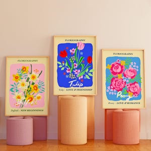 three framed artworks of different floral designs, each with a unique color scheme and style, displayed on a wall.