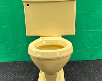 May include: A vintage, yellow toilet with a matching tank. The toilet has a classic design with a rounded bowl and a rectangular base. The tank has a curved top and a flush lever. The toilet is made of ceramic.