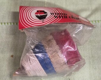 May include: A packaged wooden top with a red and white label. The top is wrapped in clear plastic and has a white, blue, tan, and red design. The label features a graphic of a spinning top and the words "WOOD WITH CO..."