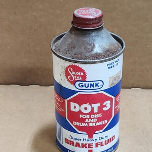 May include: A vintage Gunk DOT 3 brake fluid can. The can is cylindrical with a red and white lid. The label features a red hexagon with the text "DOT 3" and "Super Heavy Duty Brake Fluid". It contains 12 fl oz (355 ml).