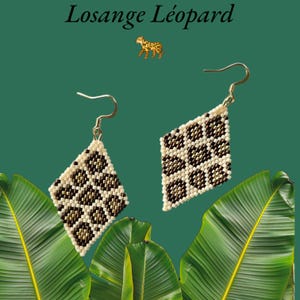 Peut inclure: Une paire de boucles d'oreilles en forme de losange, blanches et brunes, avec un motif léopard. Les boucles d'oreilles sont suspendues à des crochets dorés.