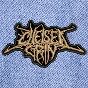 May include: Black and gold embroidered patch with the text "Chelsea Grin" in a stylized font.