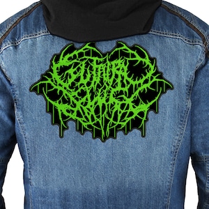 Puede incluir: Parche bordado verde y negro con el texto "GUTTERAL" en una fuente gótica.