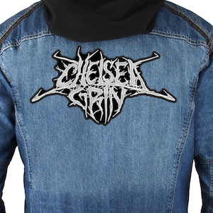 以下が含まれることがあります： 後ろに「Chelsea Grin」と刺繍された白いパッチが付いたデニムジャケットです。