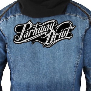 May include: A blue denim jacket with brown stitching and a white embroidered patch that says "Parkway Drive" on the back.