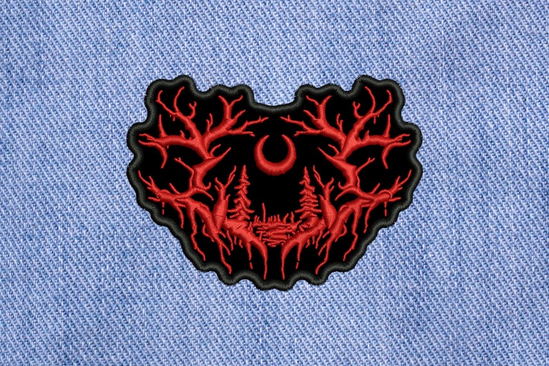May include: Black and red embroidered patch with a crescent moon and two trees in the center. The trees have branches that extend out to the sides and form a heart shape.