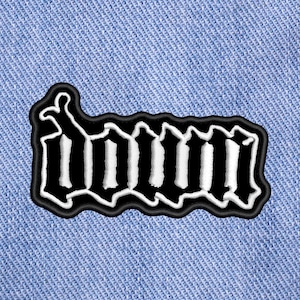 May include: Black and white embroidered patch with the word "DOWN" in a gothic font style.