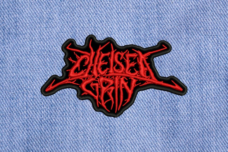 May include: Red embroidered patch with the words "Chelsea Grin" in a black outline. The patch is on a blue denim background.