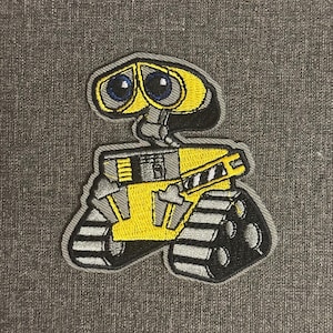 May include: Embroidered patch of the animated character Wall-E. The patch depicts Wall-E's yellow body, grey treads, and blue eyes. The patch is outlined in grey and is set against a grey fabric background.