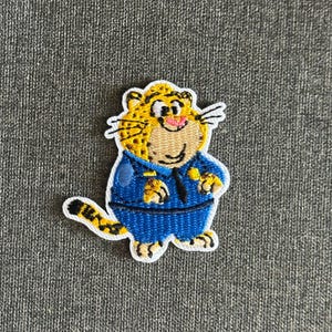 Könnte beinhalten: Gestickter Aufnäher mit einer Cartoon-Leopardfigur in blauer Uniform und schwarzer Krawatte. Der Leopard hat gelbes Fell mit schwarzen Flecken, eine rosa Nase und einen lächelnden Gesichtsausdruck. Der Aufnäher hat einen weißen Rand.