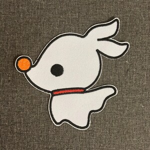 May include: White embroidered patch of a cartoon ghost dog with a black eye, orange nose, and red collar. The patch has a black outline and is on a grey background. The design is inspired by a well-known animated film.