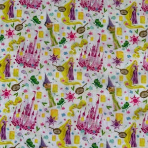May include: White fabric with a repeating pattern of a pink castle, a blonde woman in a purple dress, a frying pan, a yellow tower, a green chameleon, and a yellow sun with a flower.