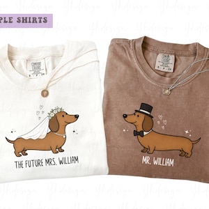 Puede incluir: Dos camisetas Comfort Colors, una crema y otra marrón, con ilustraciones de perros salchicha. La camiseta crema dice "The Future Mrs. William" y la camiseta marrón dice "Mr. William". Ambas camisetas tienen un collar y un dibujo de perro.