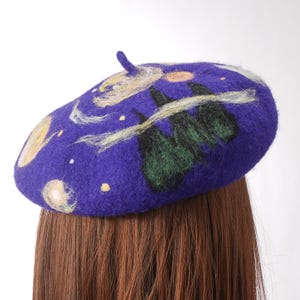 Pu&ograve; includere: Un berretto viola con un designo fantasioso che presenta un cielo notturno stellato, alberi e nuvole vorticose. Il berretto &egrave; fatto di feltro e ha una consistenza morbida e confortevole.