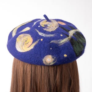 Pu&ograve; includere: Un berretto blu con un designo di notte stellata bianco e giallo. Il berretto &egrave; fatto di feltro e ha una texture morbida e confortevole.