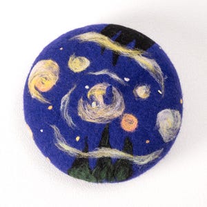 Pu&ograve; includere: Un berretto di feltro blu con un design dipinto a mano ispirato a "La notte stellata" di Vincent van Gogh. Il berretto presenta linee gialle e bianche vorticose, cerchi gialli e arancioni e alberi neri e verdi.