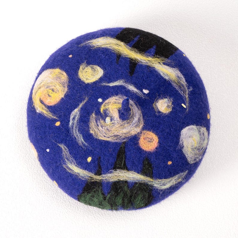 Pu&ograve; includere: Un berretto di feltro blu con un design dipinto a mano ispirato a "La notte stellata" di Vincent van Gogh. Il berretto presenta linee gialle e bianche vorticose, cerchi gialli e arancioni e alberi neri e verdi.