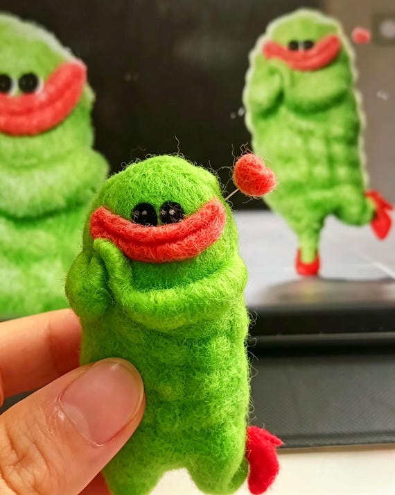 A real human needle-felts your favorite cursed internet meme into a squishy, one-of-a-kind wool desk goblin — no two are alike.