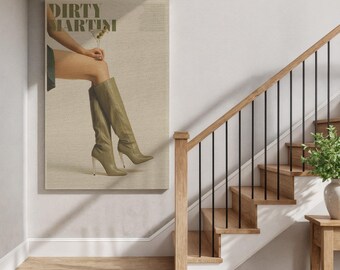 Könnte beinhalten: Ein rechteckiger Wandkunstdruck mit dem Text DIRTY MARTINI am oberen Rand. Das Bild zeigt einen Unterkörper in kniehohen, olivgrünen Stiletto-Stiefeln, wobei eine Hand ein Martiniglas mit einer Olive hält.