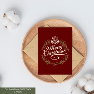 Könnte beinhalten: Eine Weihnachtsgrußkarte mit dem Schriftzug "Merry Christmas" in eleganter Schrift, umgeben von einem Kranz- und Glocken-Design. Die Karte liegt auf einem Holztablett mit einem Kraftpapierumschlag. Die Karte hat eine tiefrote Farbe.