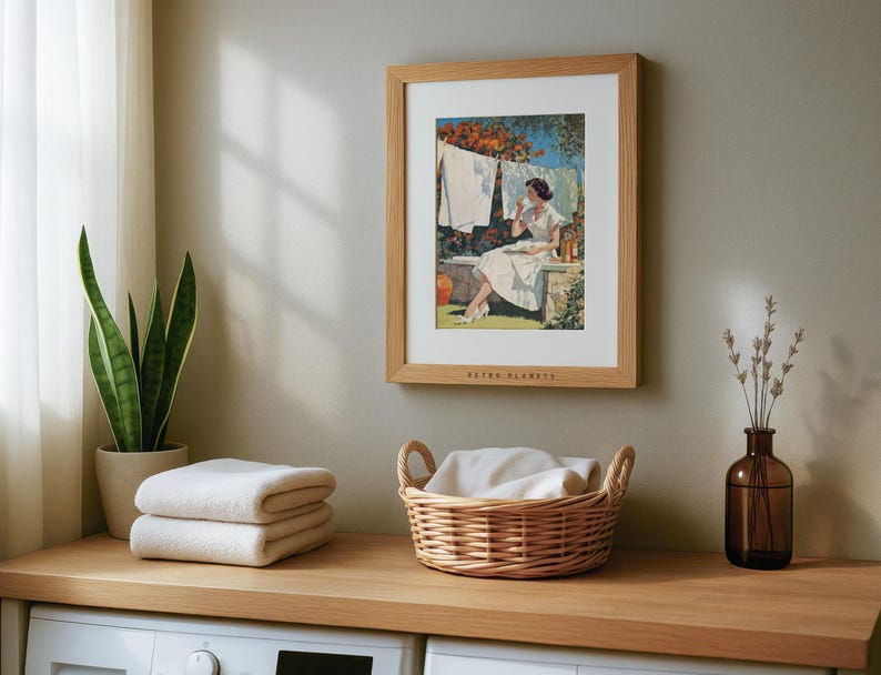 Mid-century laundry wall art in light oak frame above laundry counter with folded towels.