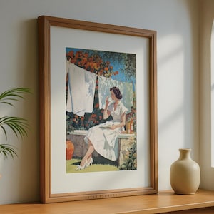 Retro laundry wall art framed in oak by sunlit window with ceramic vase and potted palm.