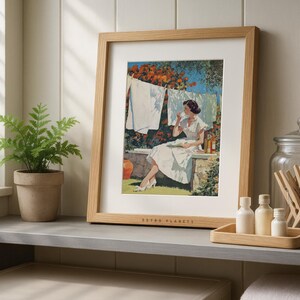 Vintage laundry poster framed in oak on gray laundry shelf with potted plant and glass jars.