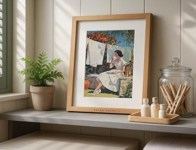 Vintage laundry poster framed in oak on gray laundry shelf with potted plant and glass jars.