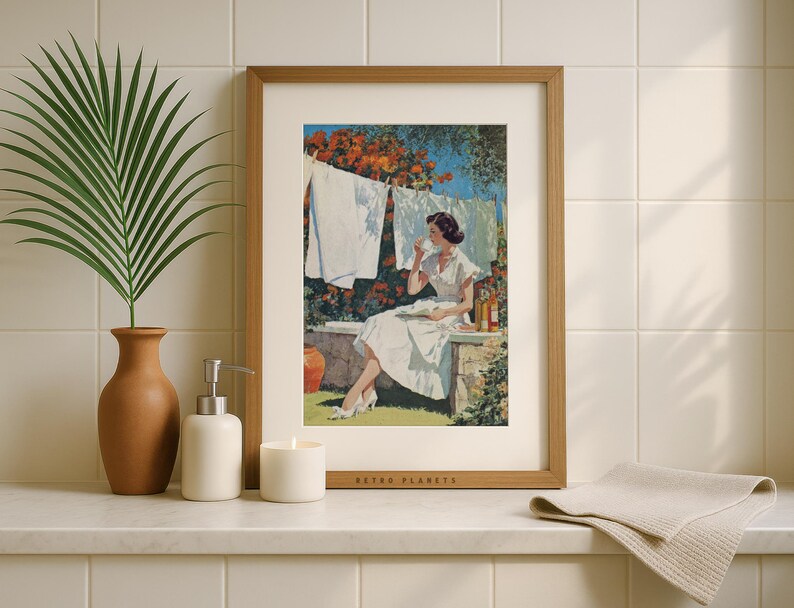 Retro clothesline wall art framed in oak on tiled bathroom shelf with candle and palm leaf.
