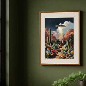 Colorful retro alien Western print framed on a deep green wall by a window, rustic farmhouse desert style.