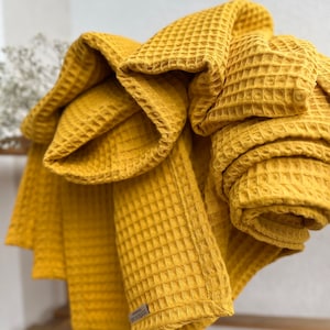 May include: A yellow waffle weave throw blanket folded and displayed. The blanket has a small tag that says "Waffle Love".