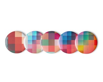 Puede incluir: Cinco botones redondos y coloridos con un diseño pixelado. Cada botón presenta un esquema de color diferente, incluyendo rojo, azul, verde y morado.