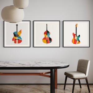 Op de afbeelding: Drie ingelijste prints van muziekinstrumenten, elk met een geometrisch ontwerp in rood, geel, blauw en zwart. De instrumenten zijn een gitaar, een contrabas en een elektrische gitaar.
