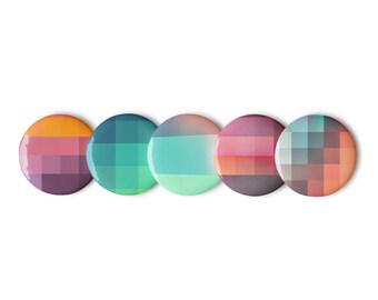 Puede incluir: Cinco botones redondos, coloridos y pixelados con un diseño degradado. Los botones están dispuestos en una fila de izquierda a derecha, con los colores pasando de naranja a morado, de verde a azul, de azul a verde, de rosa a morado y de naranja a morado.