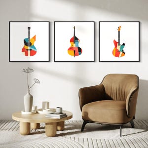 Op de afbeelding: Drie ingelijste prints van kleurrijke geometrische muziekinstrumenten. De prints tonen een gitaar, een bas en een elektrische gitaar. De prints worden getoond op een witte muur boven een bruine fauteuil en een houten salontafel.