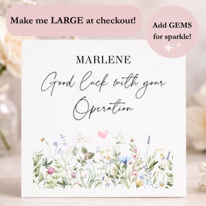 Peut inclure: Une carte blanche avec le nom "MARLENE" et le message "Good luck with your Operation" en écriture élégante. La carte présente une bordure florale avec un cœur rose et le texte "Make me LARGE at checkout!" et "Add GEMS for sparkle!"