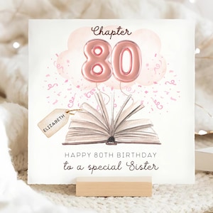 Op de afbeelding: Verjaardagskaart met een aquarel illustratie. De kaart toont een boek met de tekst "Hoofdstuk 80" in roze ballonletters, confetti en de woorden "Gelukkige 80e verjaardag aan een speciale zus". Een label leest "Elizabeth".