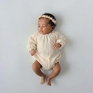 Sleeping infant dressed in the ethereal Lylou newborn romper with a delicate floral headband. The premium crinkled cotton introduces 3D depth, serving as a breathtaking studio newborn photo prop.